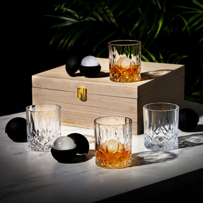 Wooden box with glasses containing a drink and ice cubes on a dark background